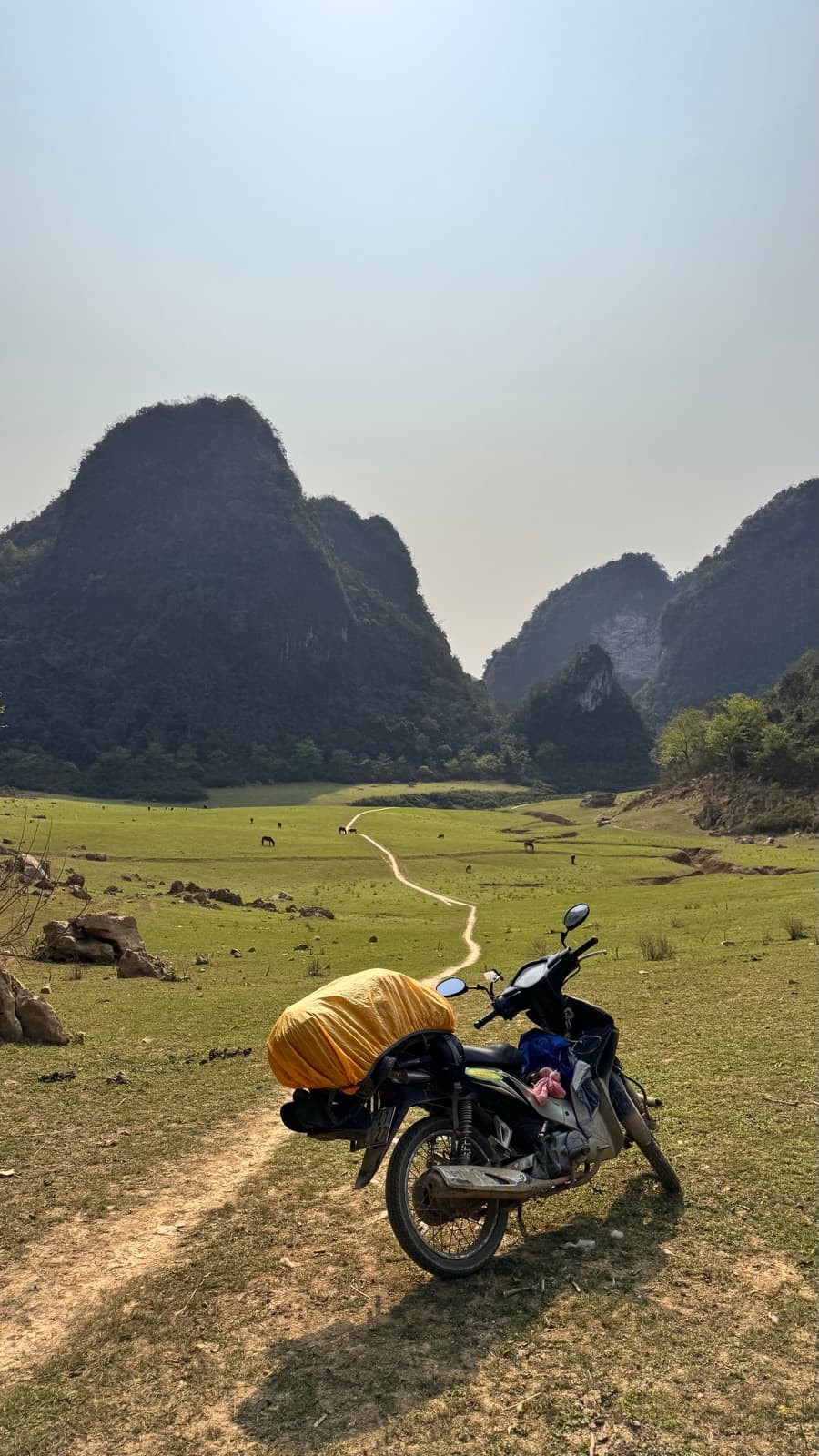 Motorbike on a grassy trail among karst peaks