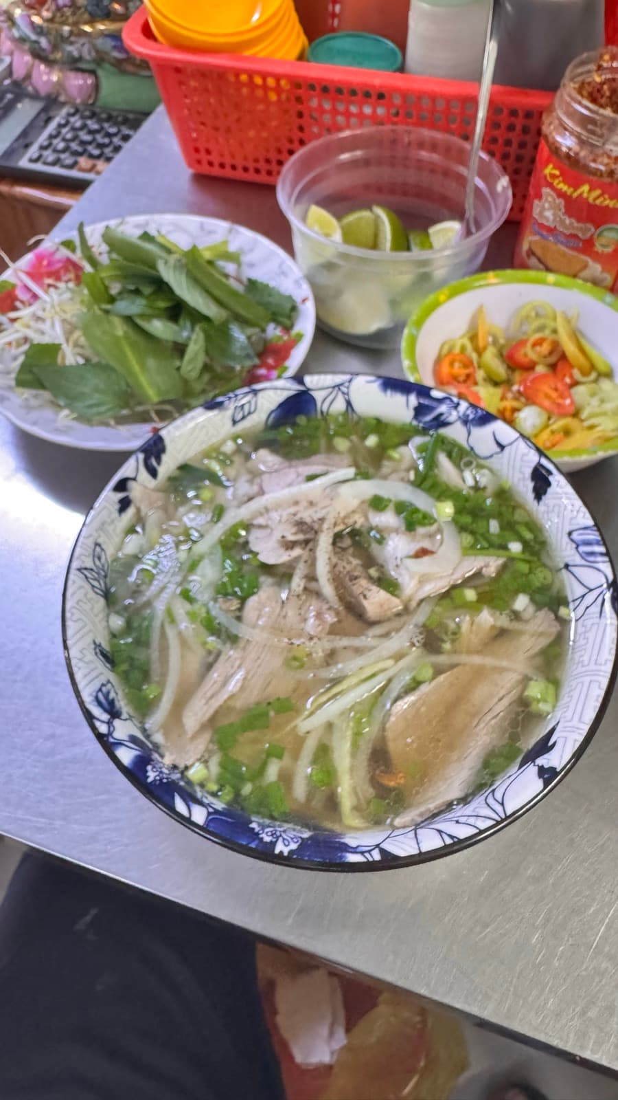 A steaming bowl of phở with fresh herbs on the side