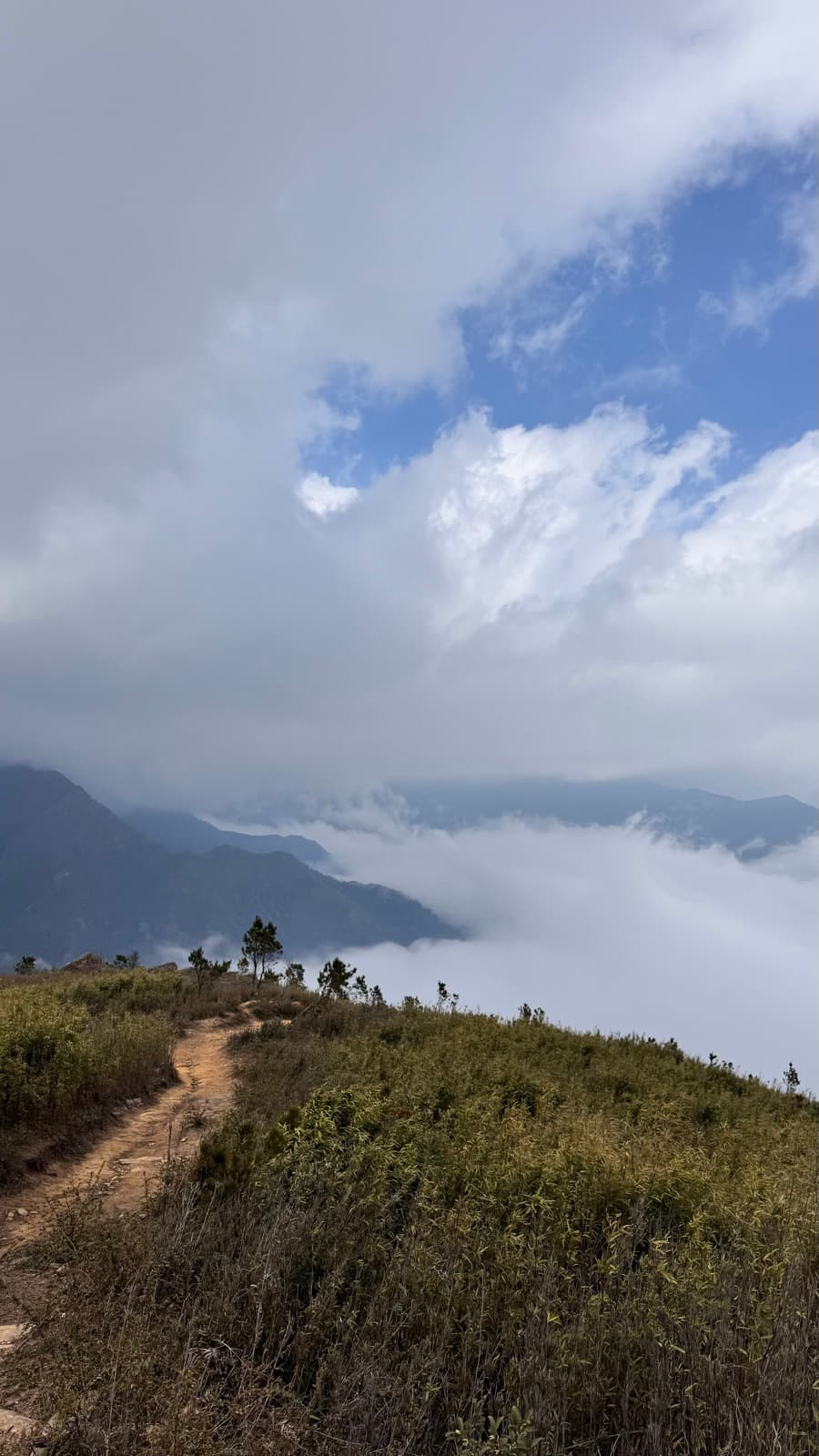 A ridge trail dropping into the clouds at Tà Xùa