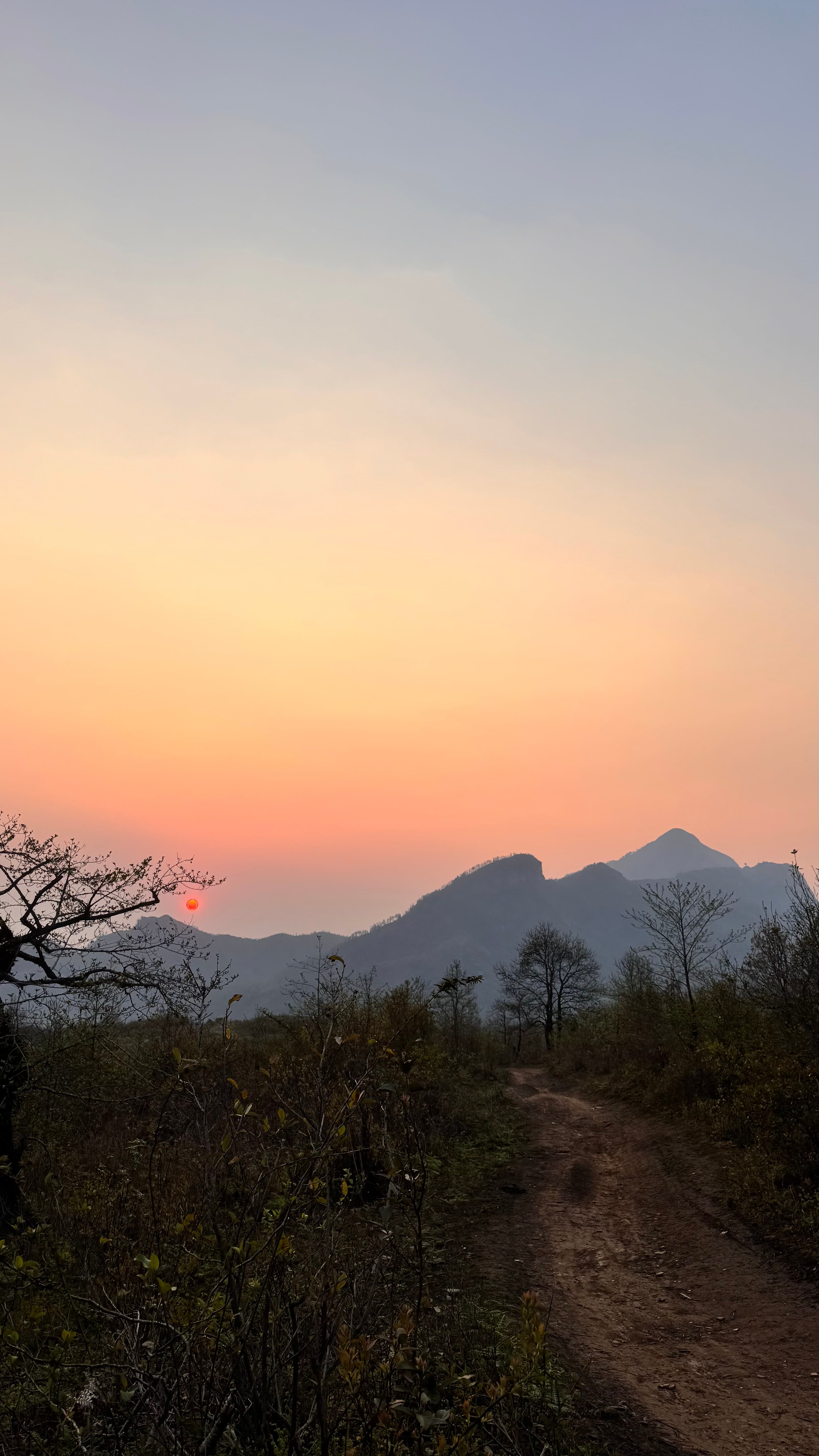 A dirt track leading toward mountains at sunset in Y Tý