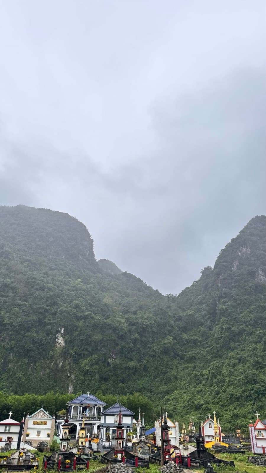 Colorful tombs at the foot of mist-shrouded karst mountains in Phong Nha